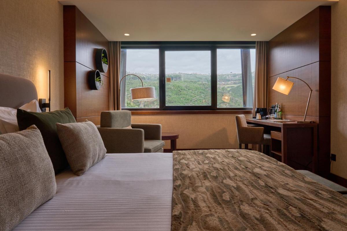 um quarto de hotel com uma cama e uma janela grande em H2otel Congress & Medical SPA em Unhais da Serra mais 61 fotografias