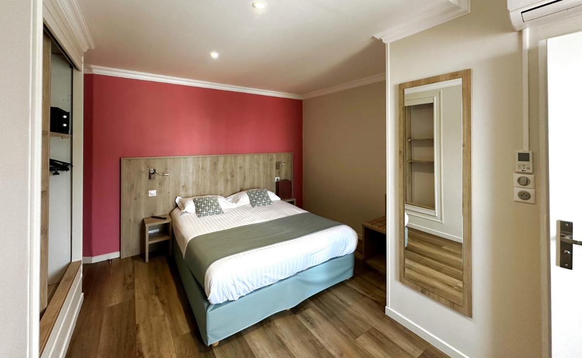 une chambre avec un lit et un mur rouge dans l'établissement Logis - Hôtel Arc en Ciel et SPA Les Sables d'Olonne, à Les Sables-dʼOlonne