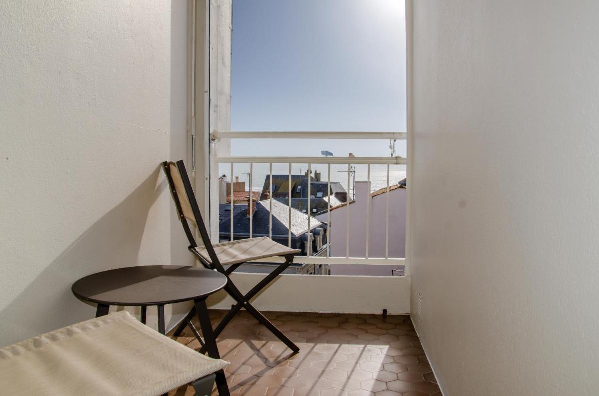 une chaise et une table dans une pièce avec une fenêtre dans l'établissement Logis - Hôtel Arc en Ciel et SPA Les Sables d'Olonne, à Les Sables-dʼOlonne
