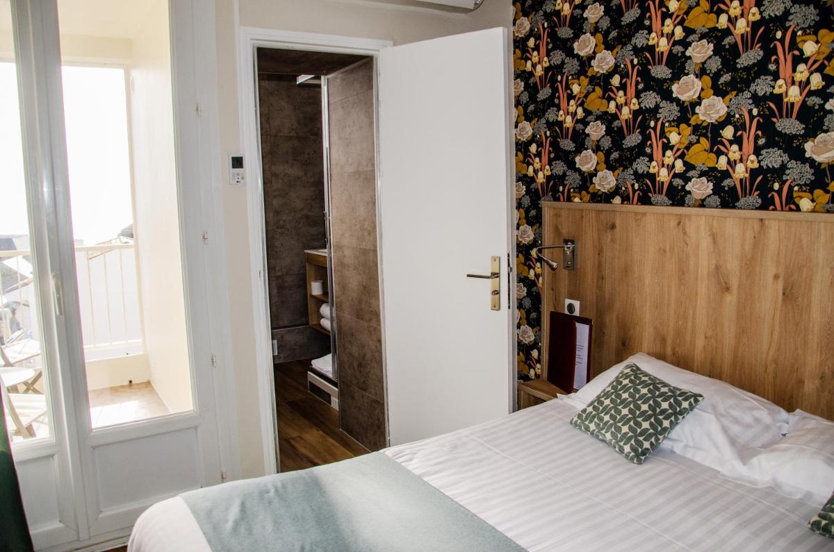 une chambre avec un lit avec un papier peint fleuri dans l'établissement Logis - Hôtel Arc en Ciel et SPA Les Sables d'Olonne, à Les Sables-dʼOlonne 3 autres photos