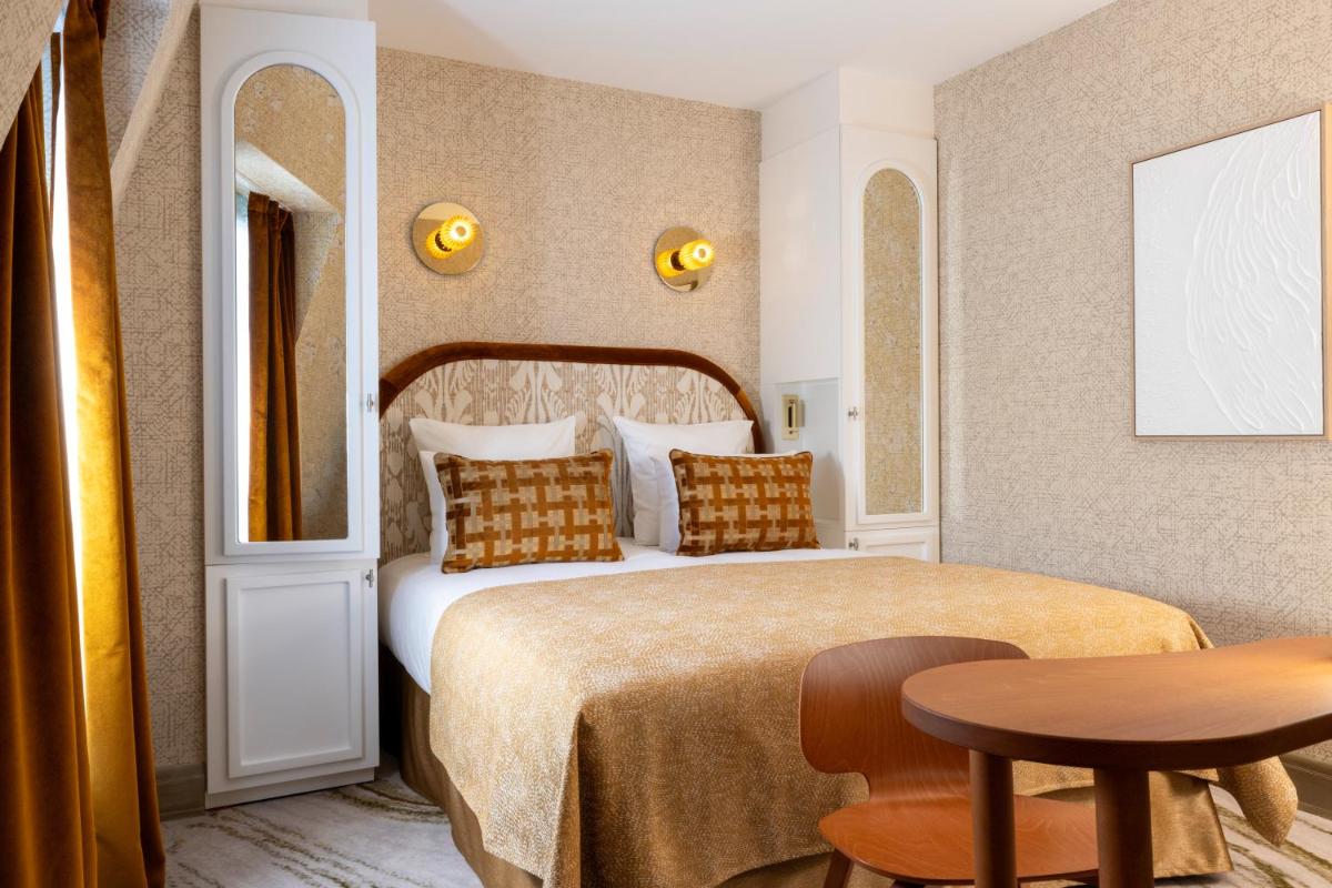 une chambre d'hôtel avec un lit et une table dans l'établissement Hotel des Carmes by Malone, à Paris