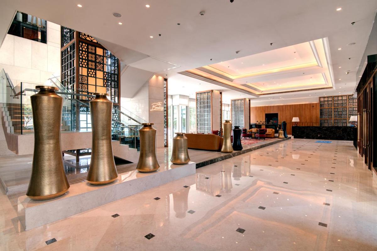 a hotel lobby with a large lobby with gold columns at Hyatt Ahmedabad in Ahmedabad
