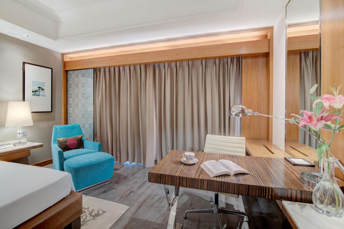a hotel room with a desk and a blue chair at Hyatt Ahmedabad in Ahmedabad