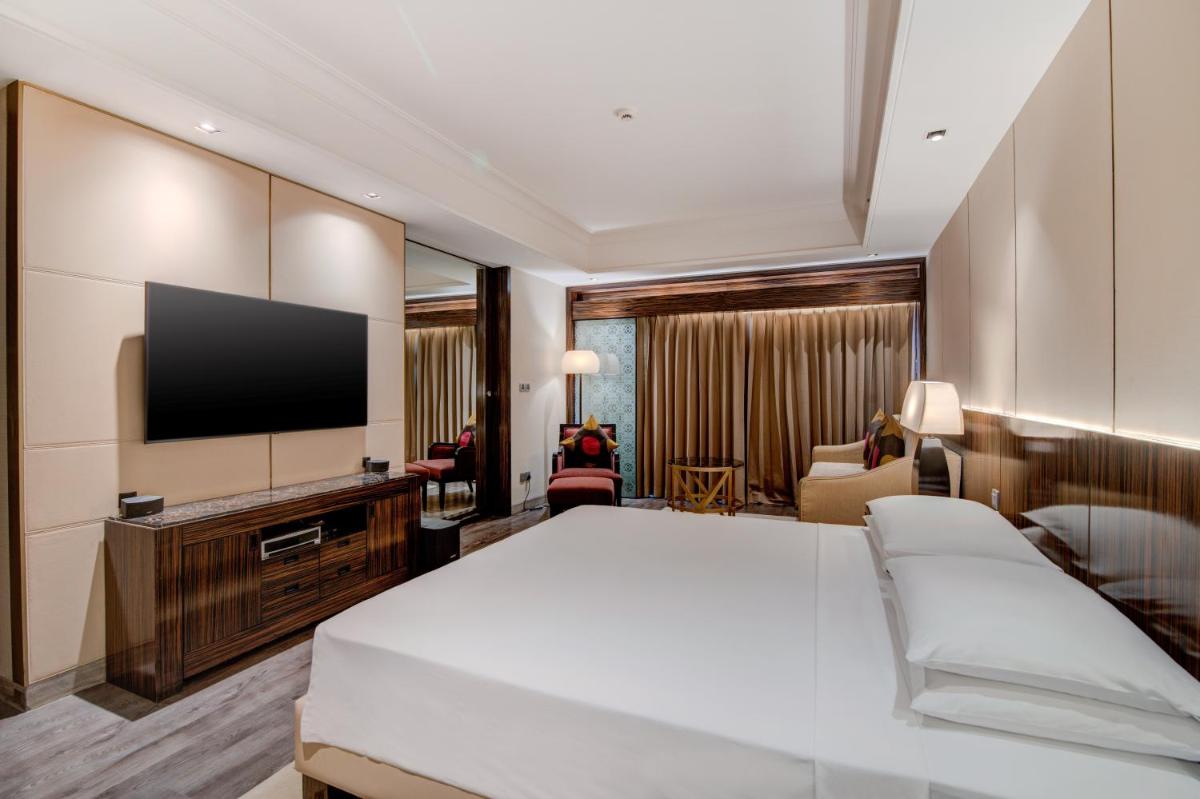 a hotel room with a bed and a flat screen tv at Hyatt Ahmedabad in Ahmedabad