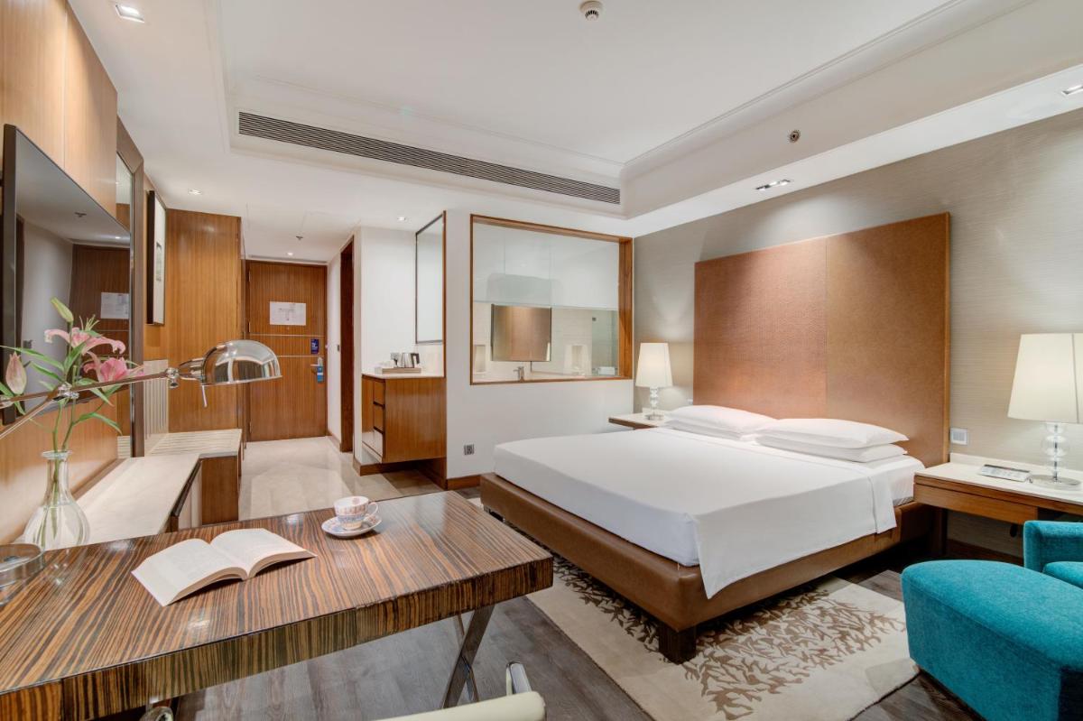 a bedroom with a bed and a desk and a room at Hyatt Ahmedabad in Ahmedabad
