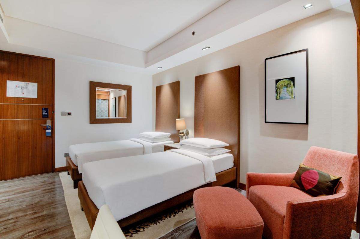 a hotel room with two beds and two chairs at Hyatt Ahmedabad in Ahmedabad