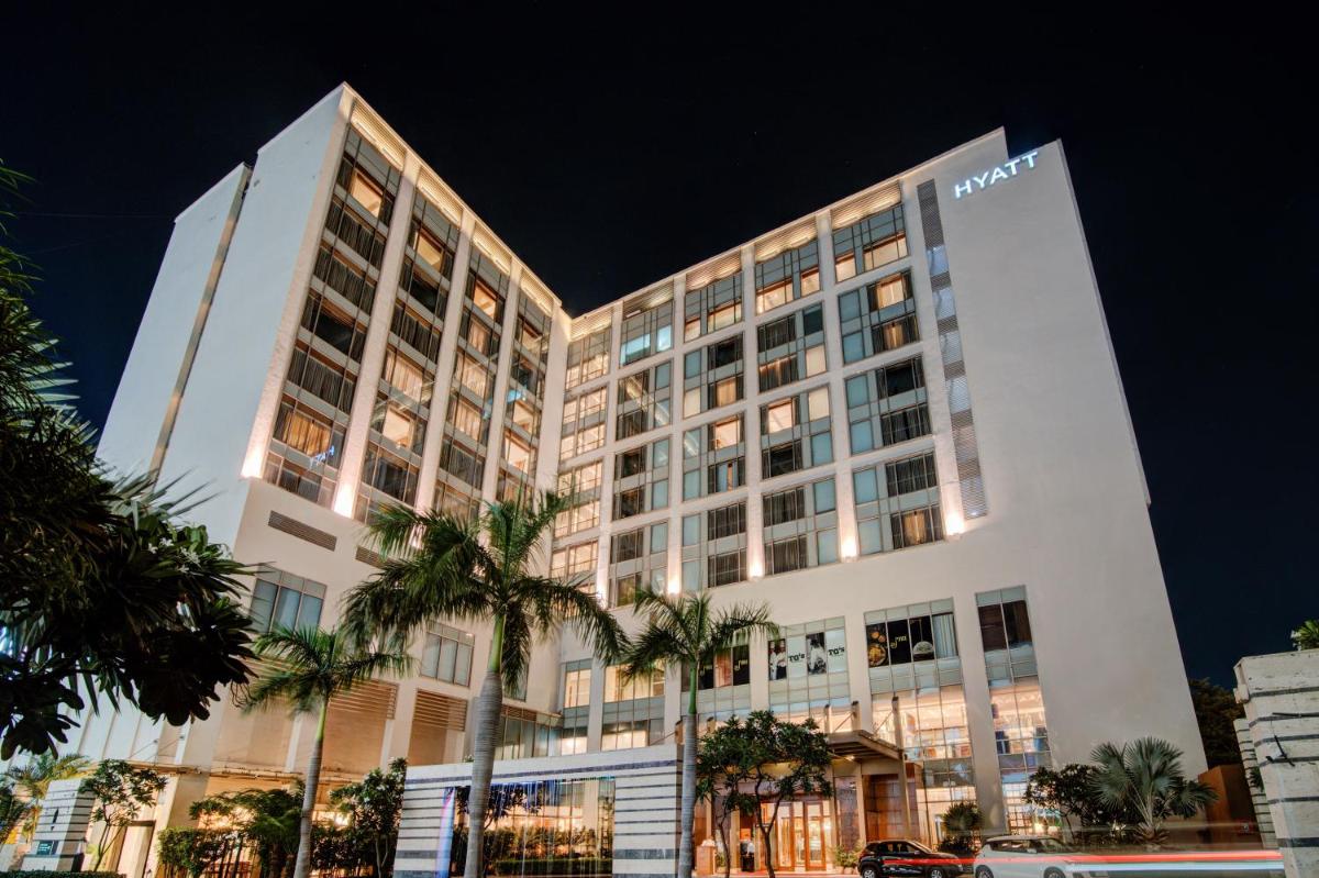 a tall building with palm trees in front of it at Hyatt Ahmedabad in Ahmedabad