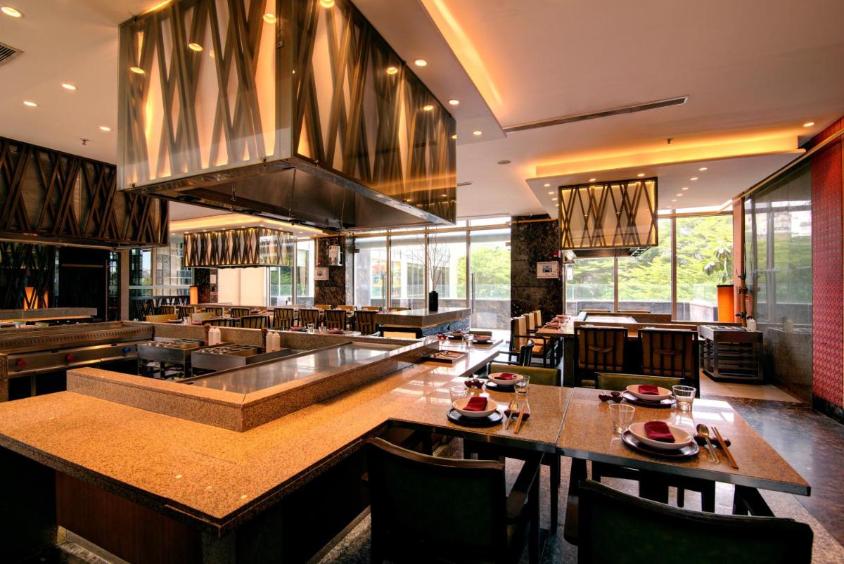 a large kitchen with tables and chairs in a restaurant at Hyatt Ahmedabad in Ahmedabad