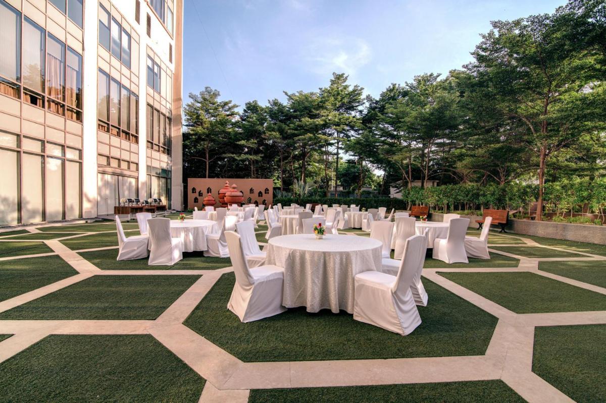 a group of tables and white chairs on a lawn at Hyatt Ahmedabad in Ahmedabad