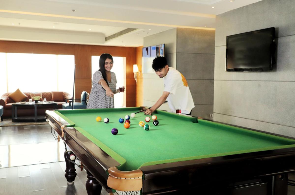 a man and a woman playing a game of pool at Hyatt Ahmedabad in Ahmedabad