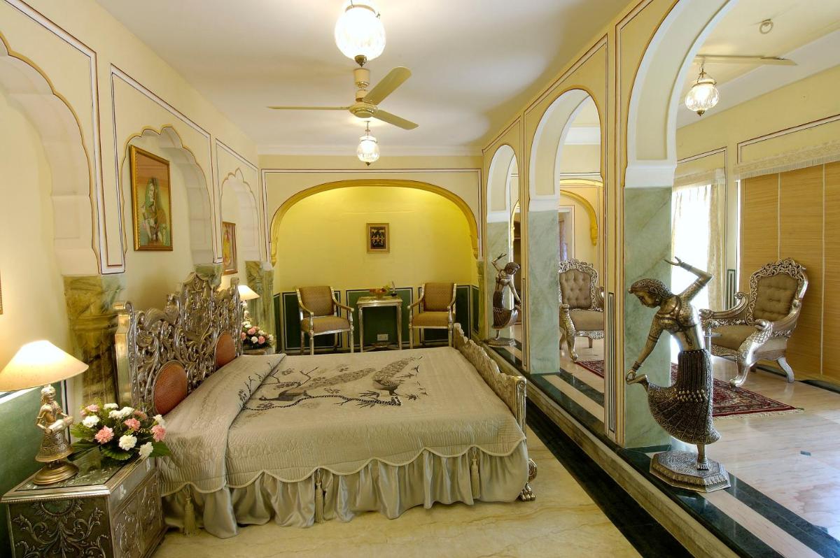 a bedroom with a bed and a table and chairs at The Raj Palace (Small Luxury Hotels of the World) in Jaipur