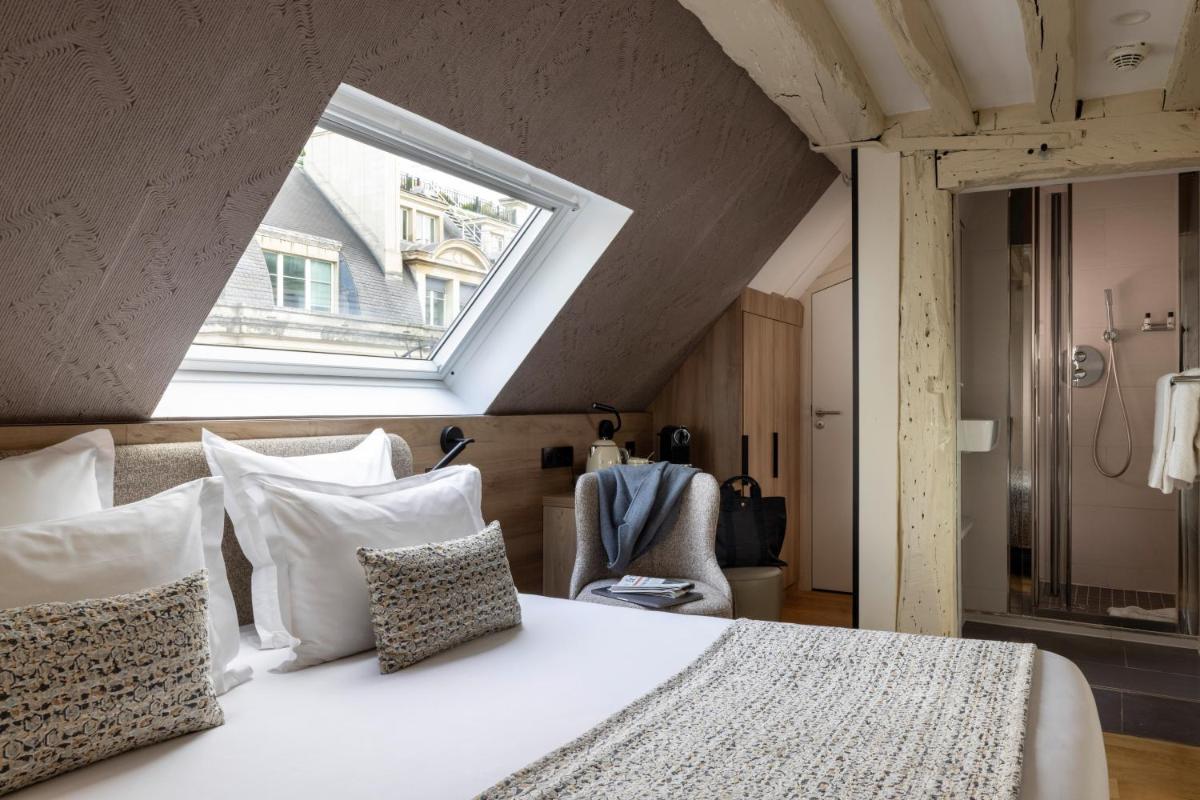 une chambre avec un lit blanc avec une lucarne dans l'établissement Hôtel Théorème, à Paris