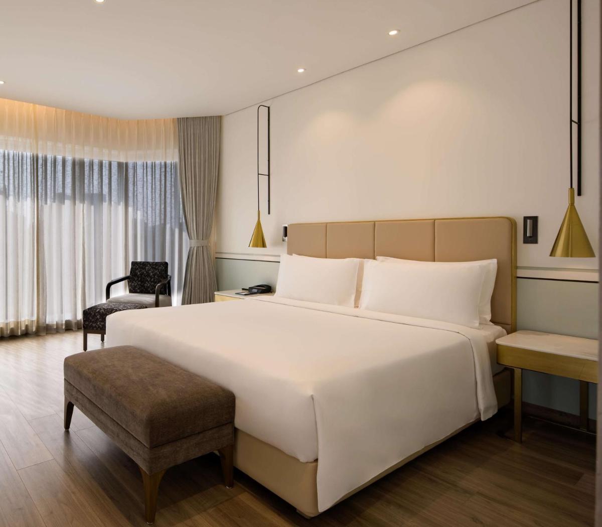 a bedroom with a large white bed and a chair at Radisson Blu Mumbai International Airport in Mumbai a bedroom with a large white bed and a chair at Radisson Blu Mumbai International Airport in Mumbai