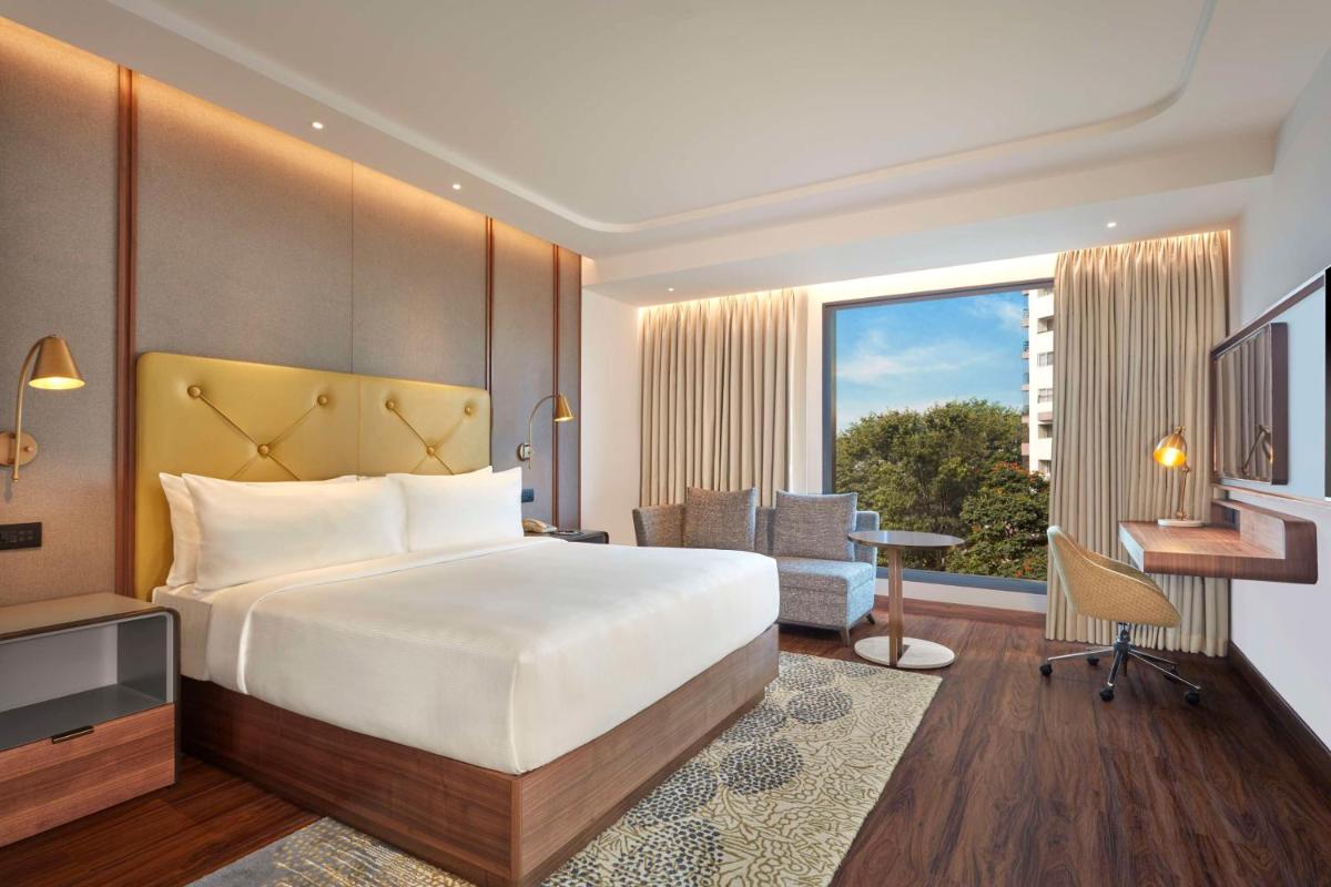 a bedroom with a bed and a desk and a window at Doubletree By Hilton Bengaluru Whitefield in Bengaluru