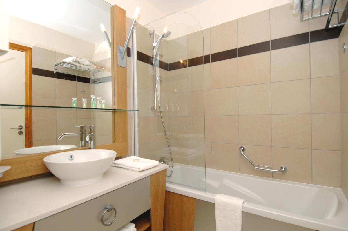 une salle de bain avec une baignoire, un lavabo et une douche dans l'établissement Résidence Prestige Odalys Edenarc, à Arc 1800