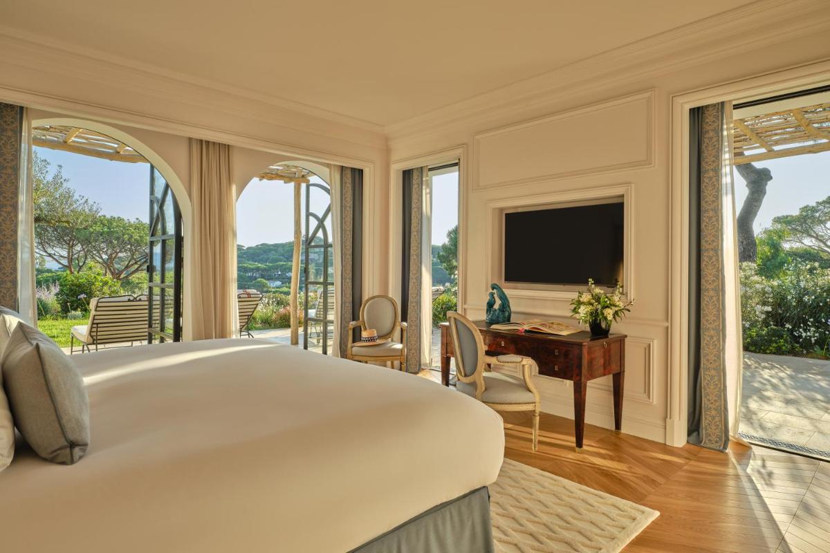 une chambre avec un grand lit blanc et un bureau dans l'établissement Airelles Château de la Messardière, à Saint-Tropez