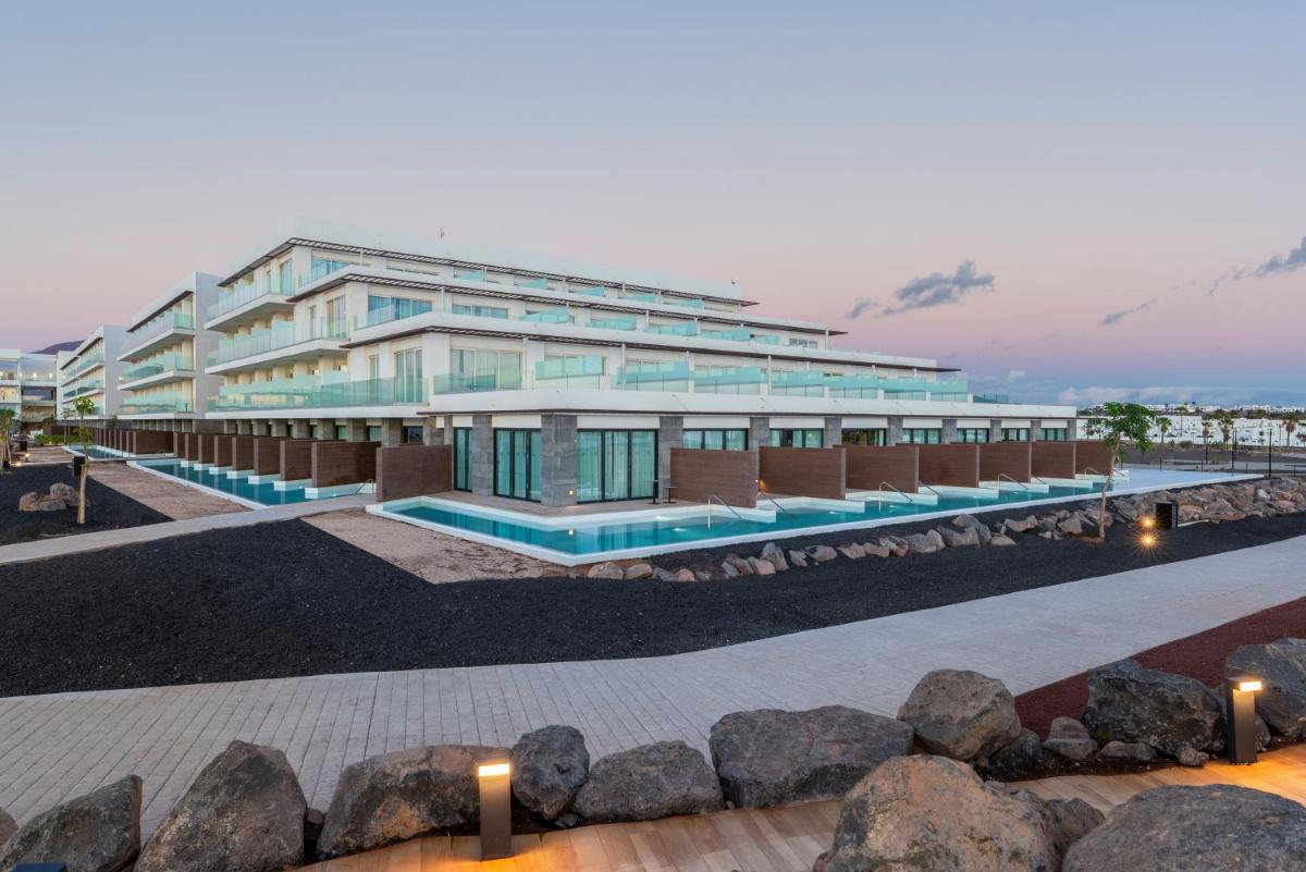 Un gran edificio con una piscina en frente. en Barceló Playa Blanca Royal Level - Adults Only, en Playa Blanca