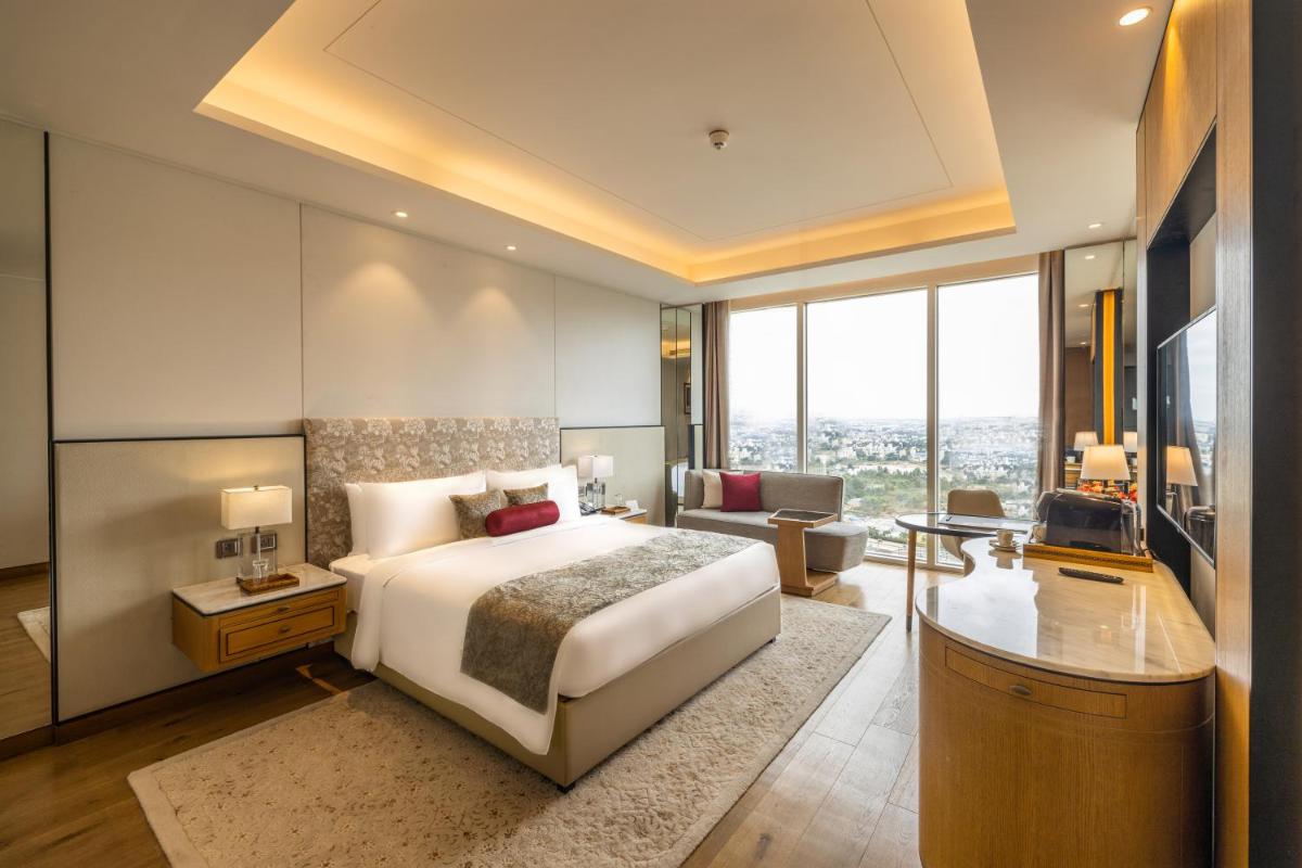 a bedroom with a large bed and a living room at The Leela Bhartiya City Bengaluru in Bengaluru a bedroom with a large bed and a living room at The Leela Bhartiya City Bengaluru in Bengaluru