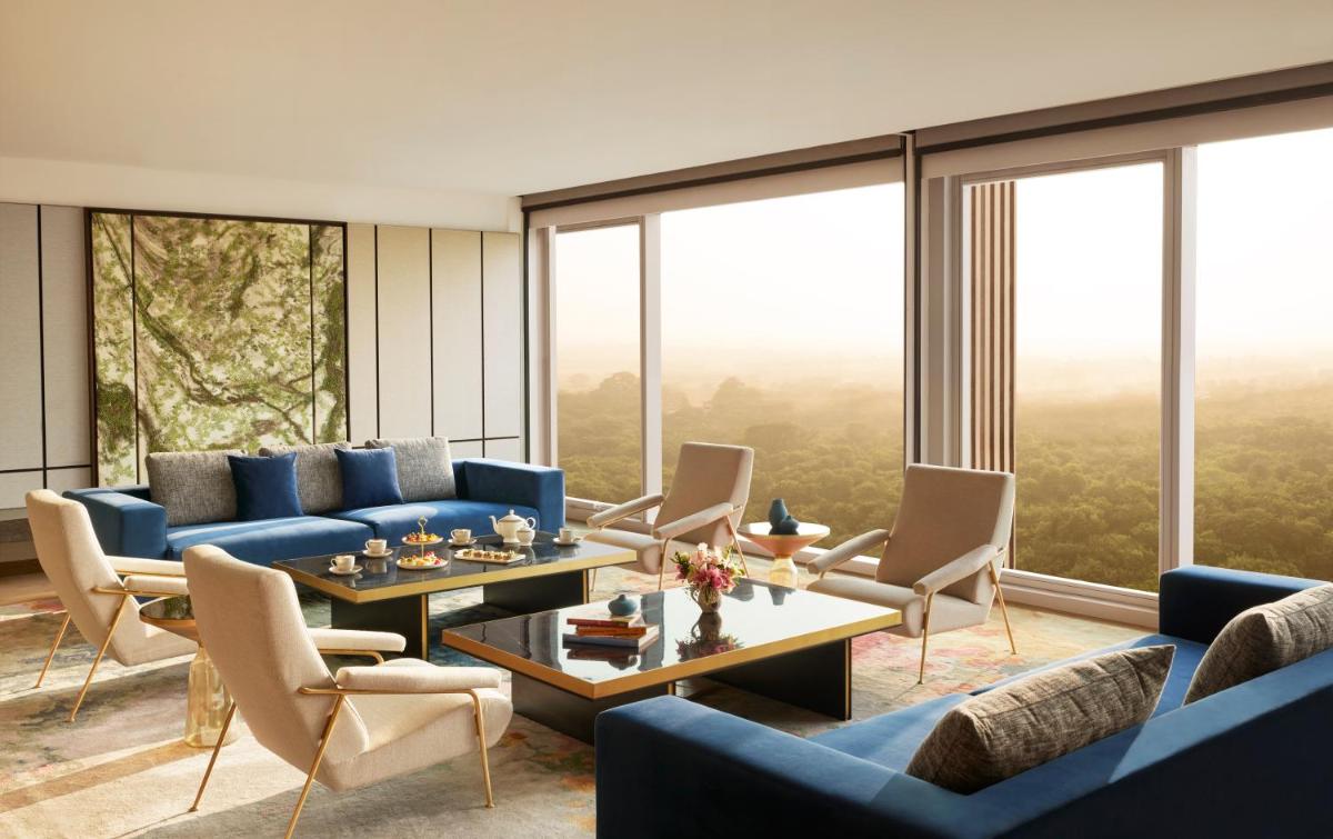 a living room with blue couches and tables and large windows at Taj The Trees, Mumbai in Mumbai