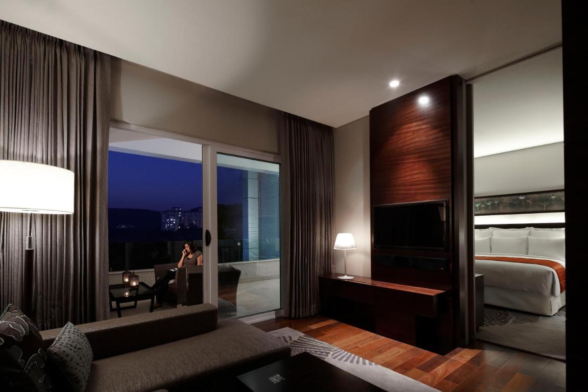 a living room with a bed and a large window at JW Marriott Pune in Pune