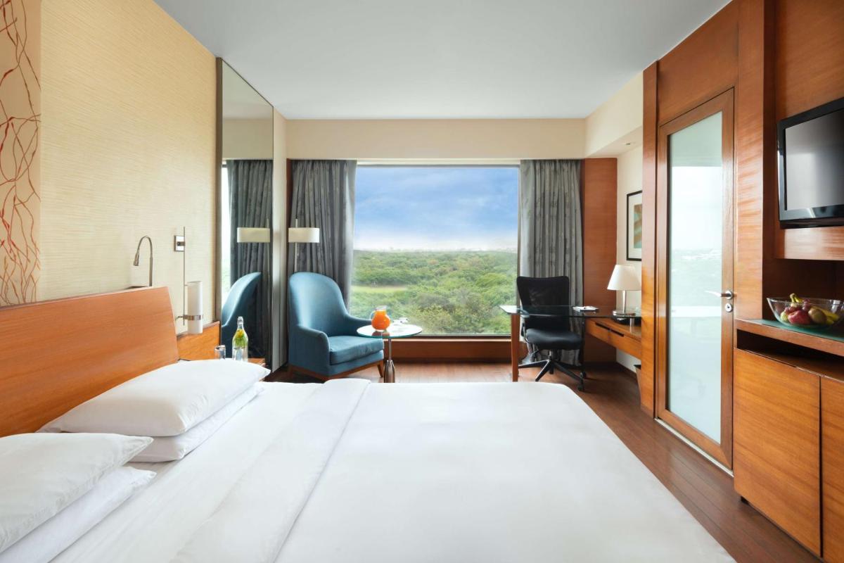 a hotel room with a large bed and a large window at Hyatt Pune in Pune