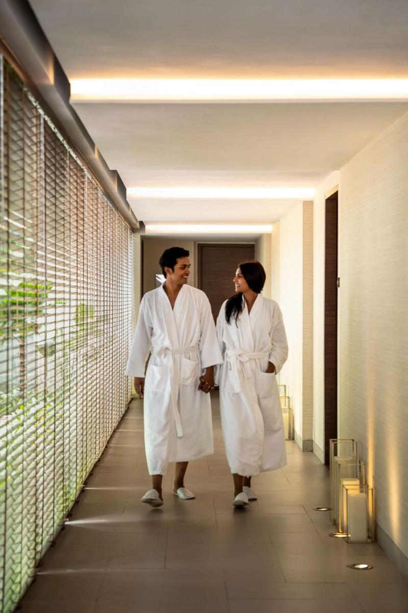 two men in white robes walking down a hallway at Hyatt Pune in Pune