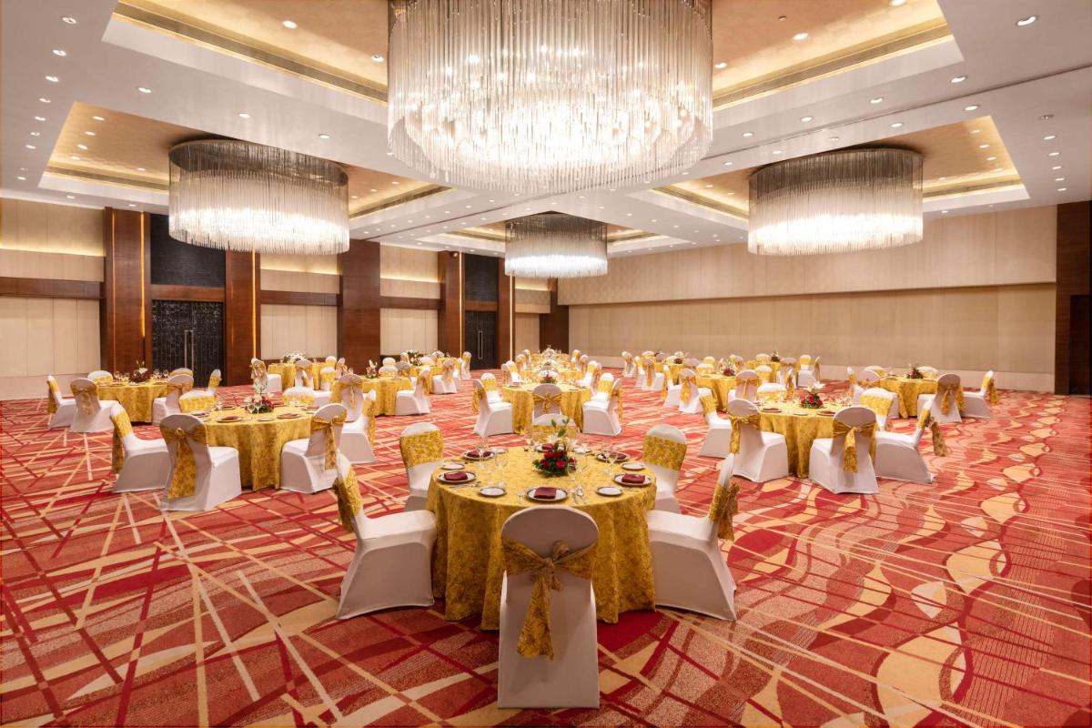 a large banquet hall with tables and chairs and chandeliers at Hyatt Pune in Pune