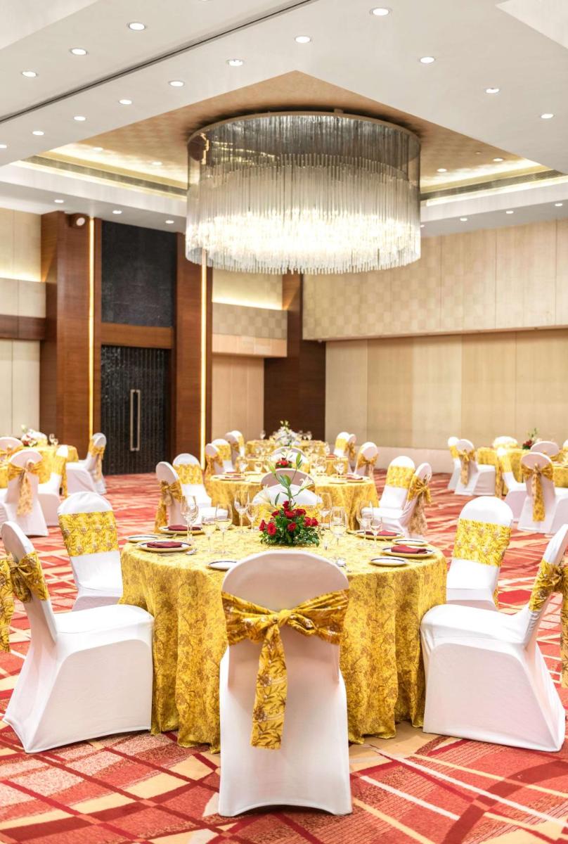 a banquet hall with tables and chairs and a chandelier at Hyatt Pune in Pune