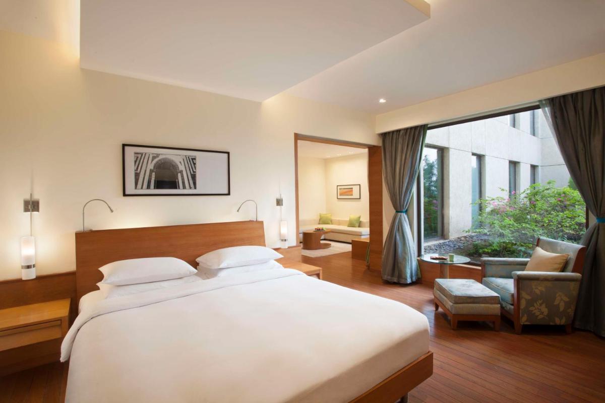 a bedroom with a large bed and a large window at Hyatt Pune in Pune