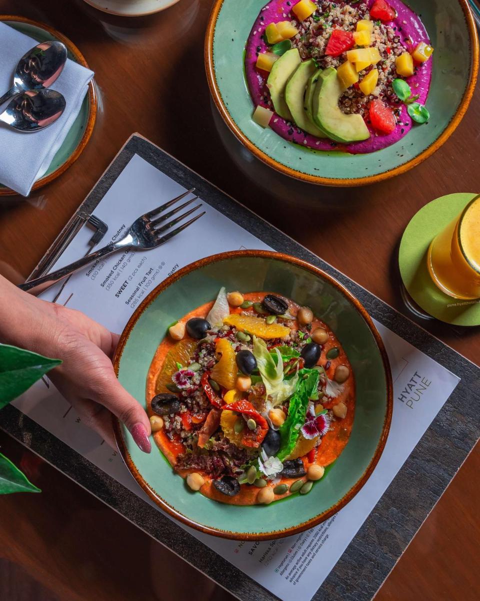 a person holding a plate of food on a table at Hyatt Pune in Pune