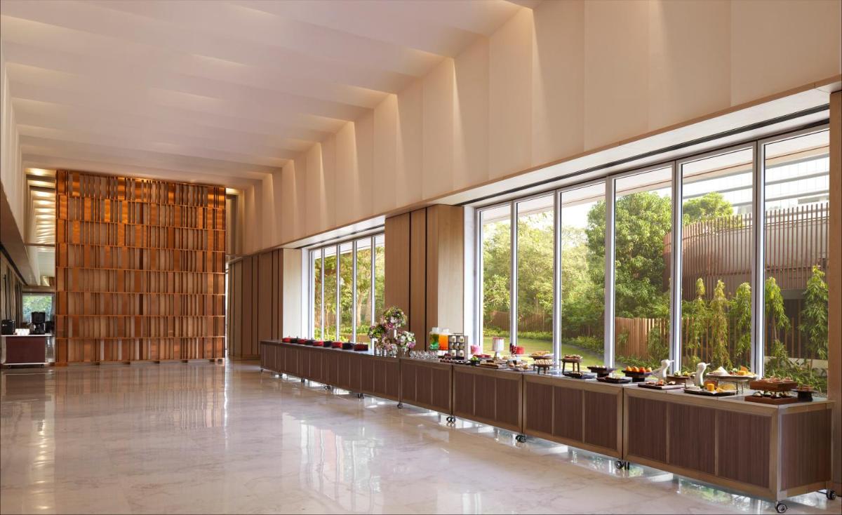 a lobby with a long row of tables and windows at Taj The Trees, Mumbai in Mumbai