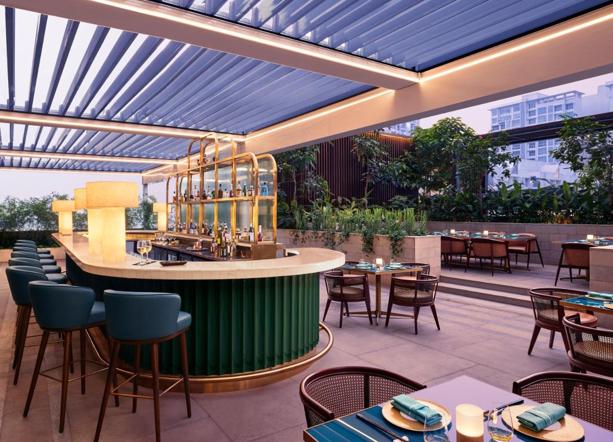 an outdoor restaurant with a bar and tables and chairs at Taj The Trees, Mumbai in Mumbai
