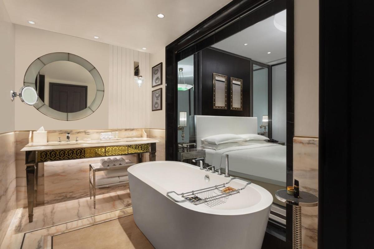 a bathroom with a tub and a bed and a mirror at ITC Narmada, a Luxury Collection Hotel, Ahmedabad in Ahmedabad