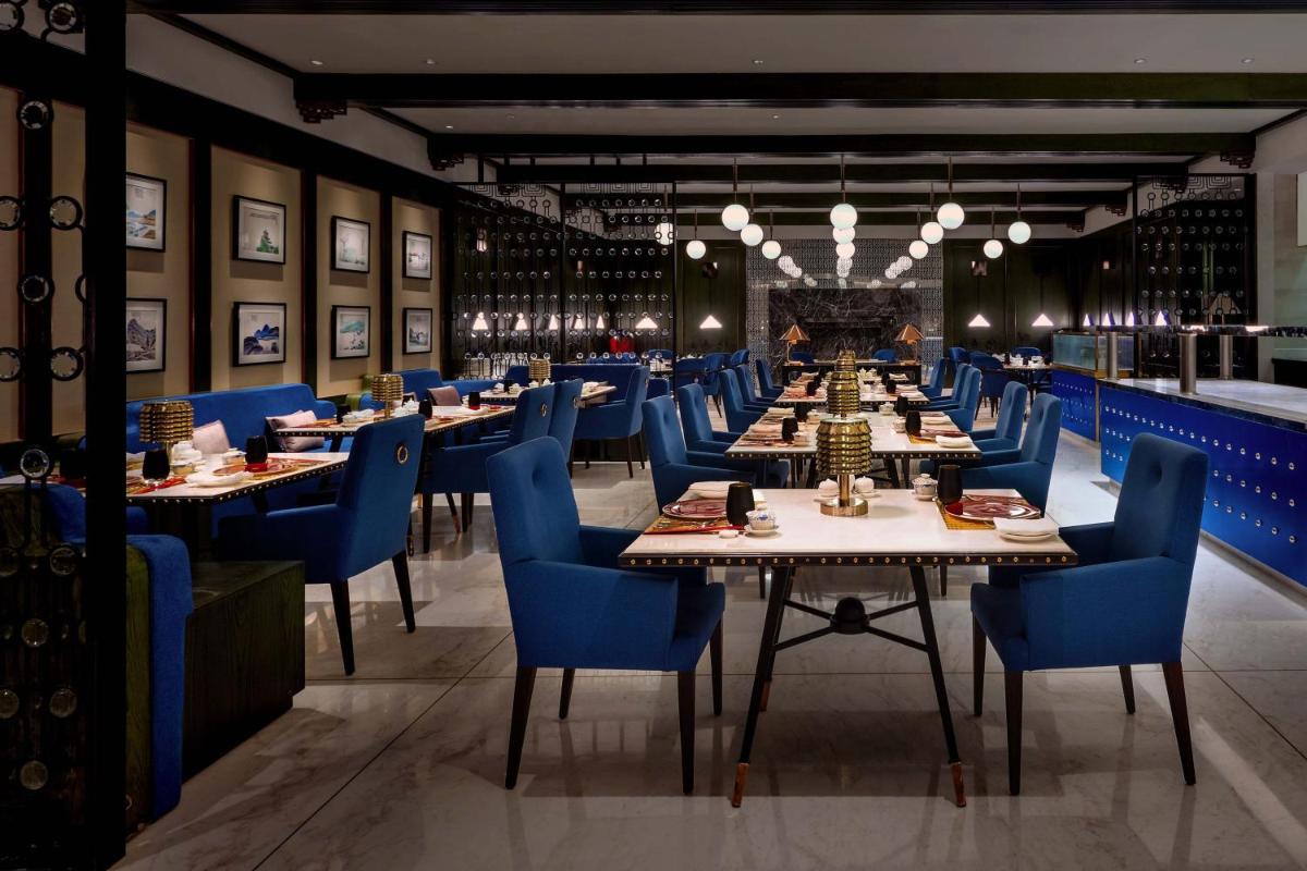 a dining room with tables and blue chairs at ITC Narmada, a Luxury Collection Hotel, Ahmedabad in Ahmedabad