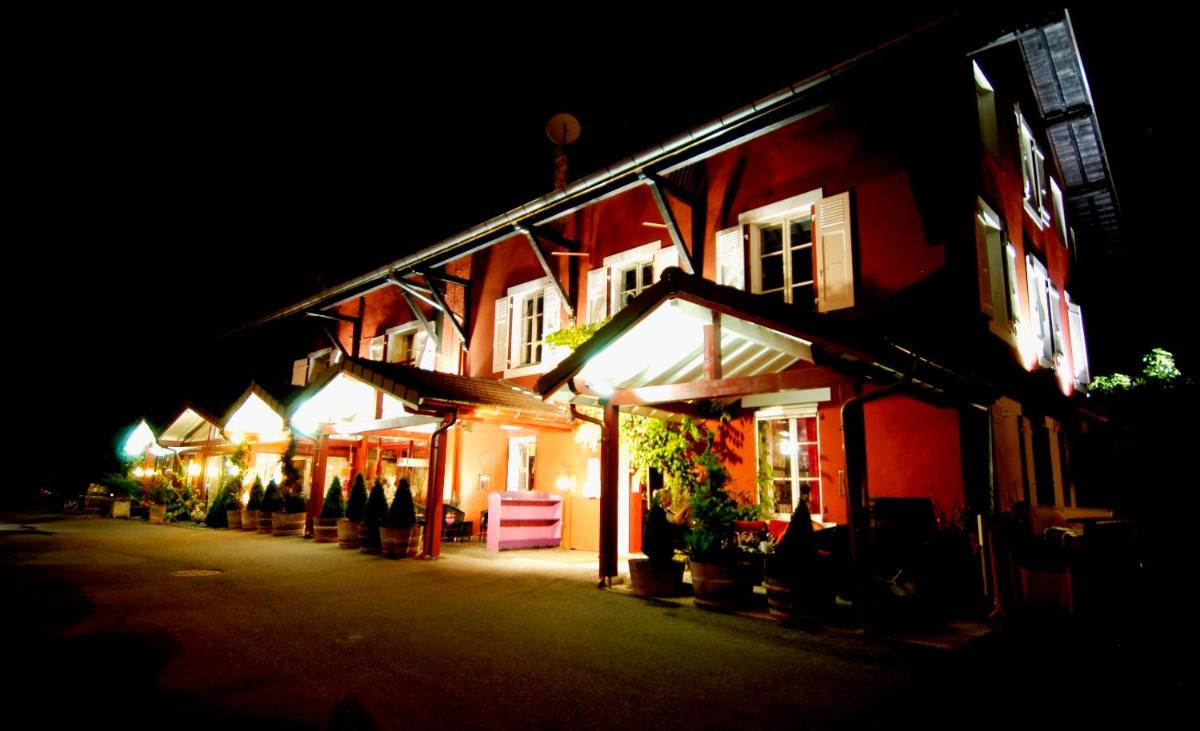 Une rangée de bâtiments la nuit avec des gens debout à l'extérieur dans l'établissement Auberge De Maison Rouge, à Vétraz-Monthoux