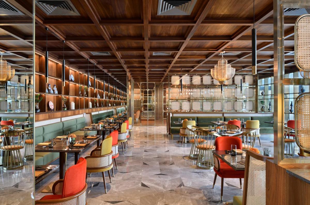 a restaurant with tables and chairs and a bar at Taj Amer, Jaipur in Jaipur