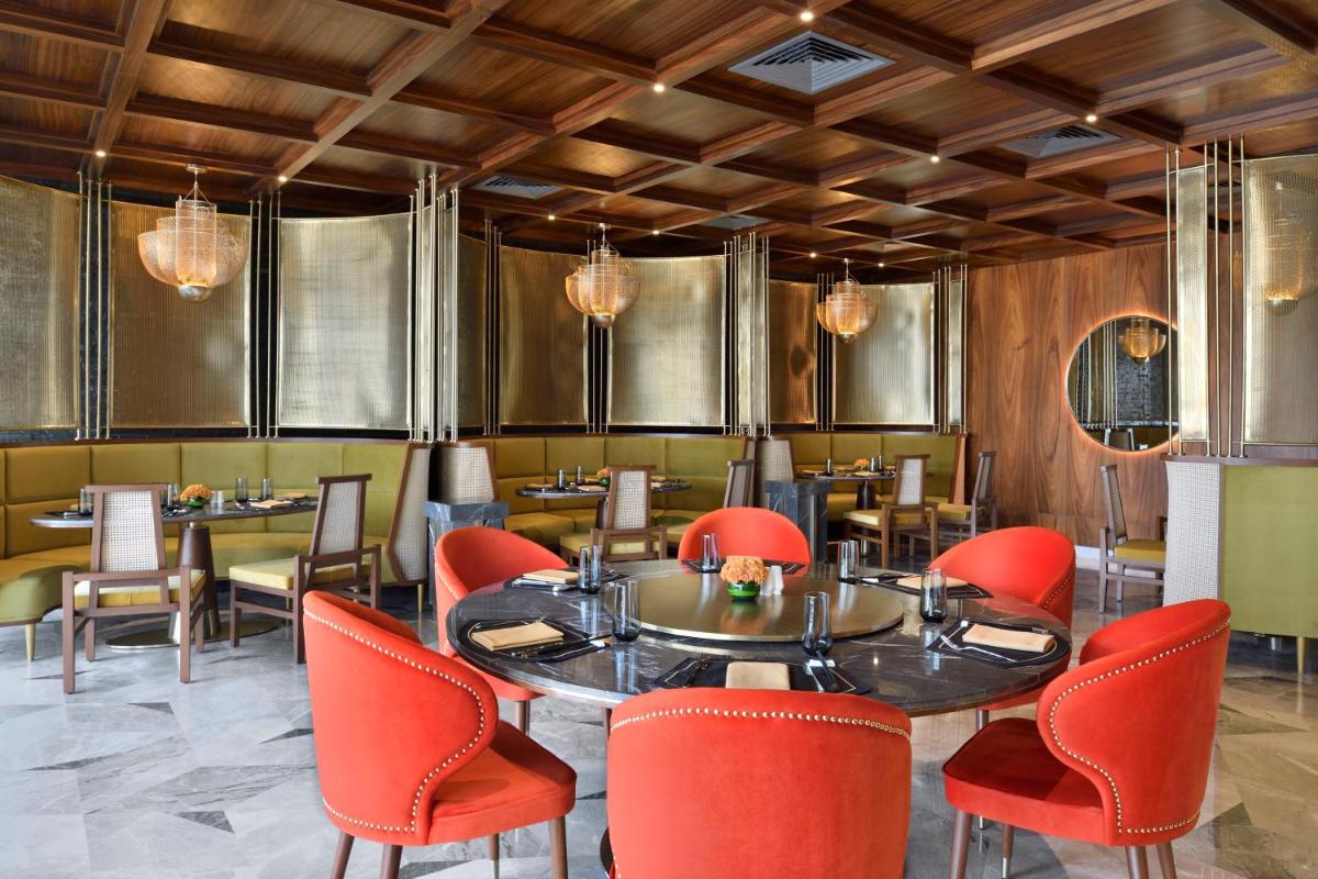 a dining room with a table and red chairs at Taj Amer, Jaipur in Jaipur