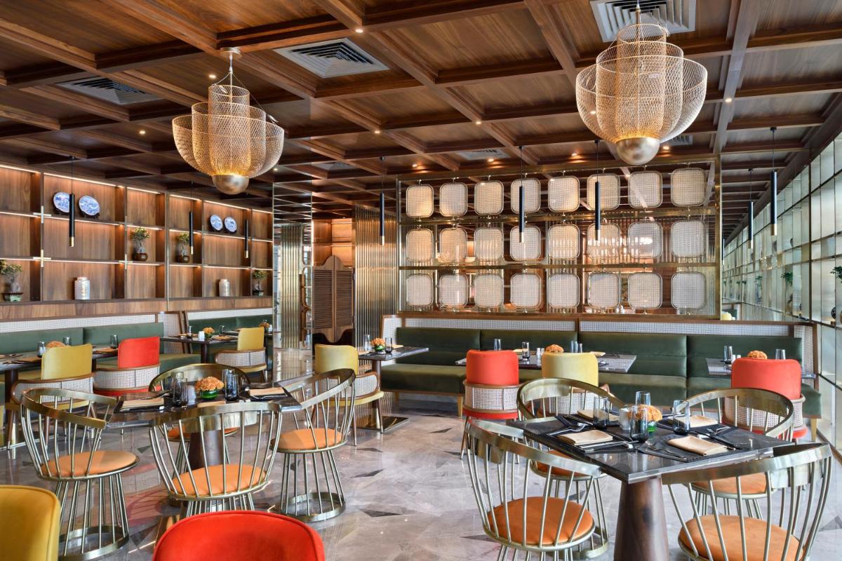 a restaurant with tables and chairs and chandeliers at Taj Amer, Jaipur in Jaipur