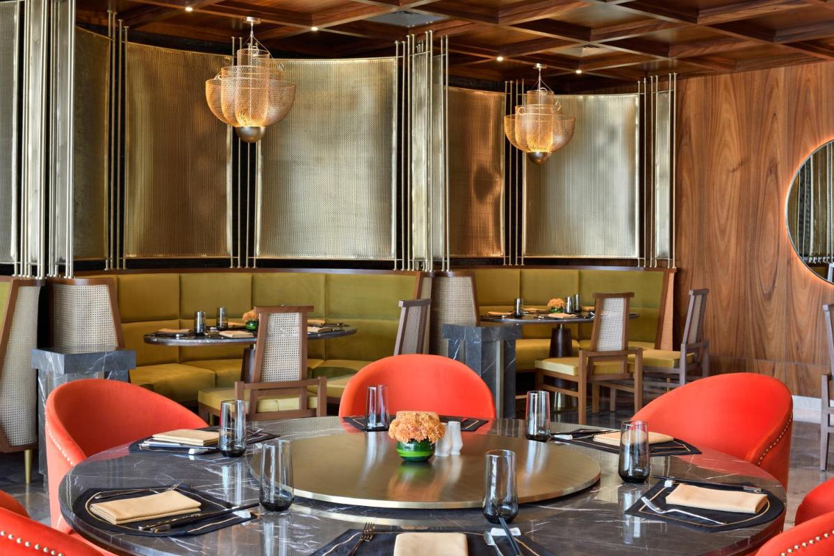 a dining room with tables and chairs and chandeliers at Taj Amer, Jaipur in Jaipur