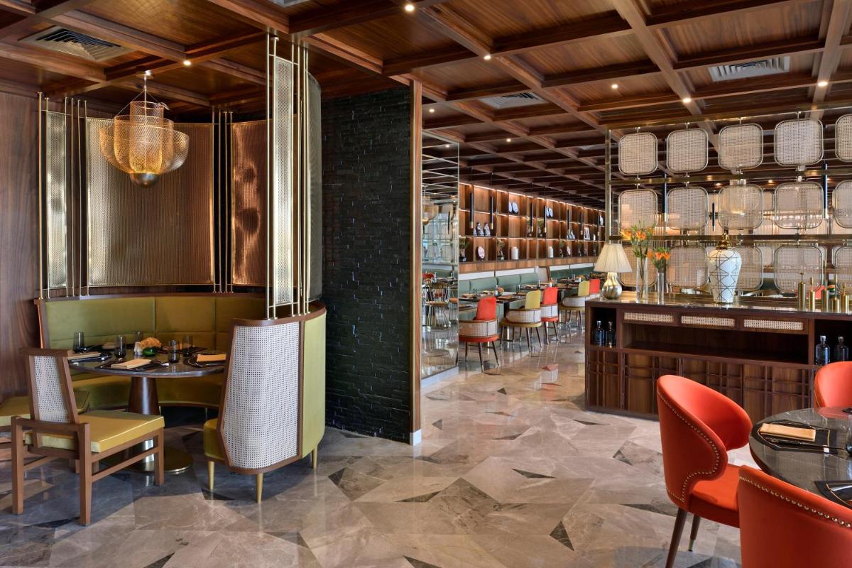 a restaurant with tables and chairs and a bar at Taj Amer, Jaipur in Jaipur