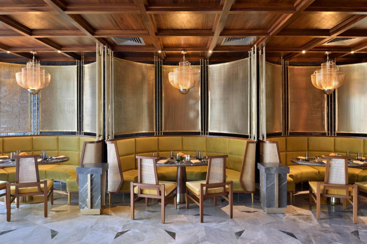 a restaurant with tables and chairs and chandeliers at Taj Amer, Jaipur in Jaipur