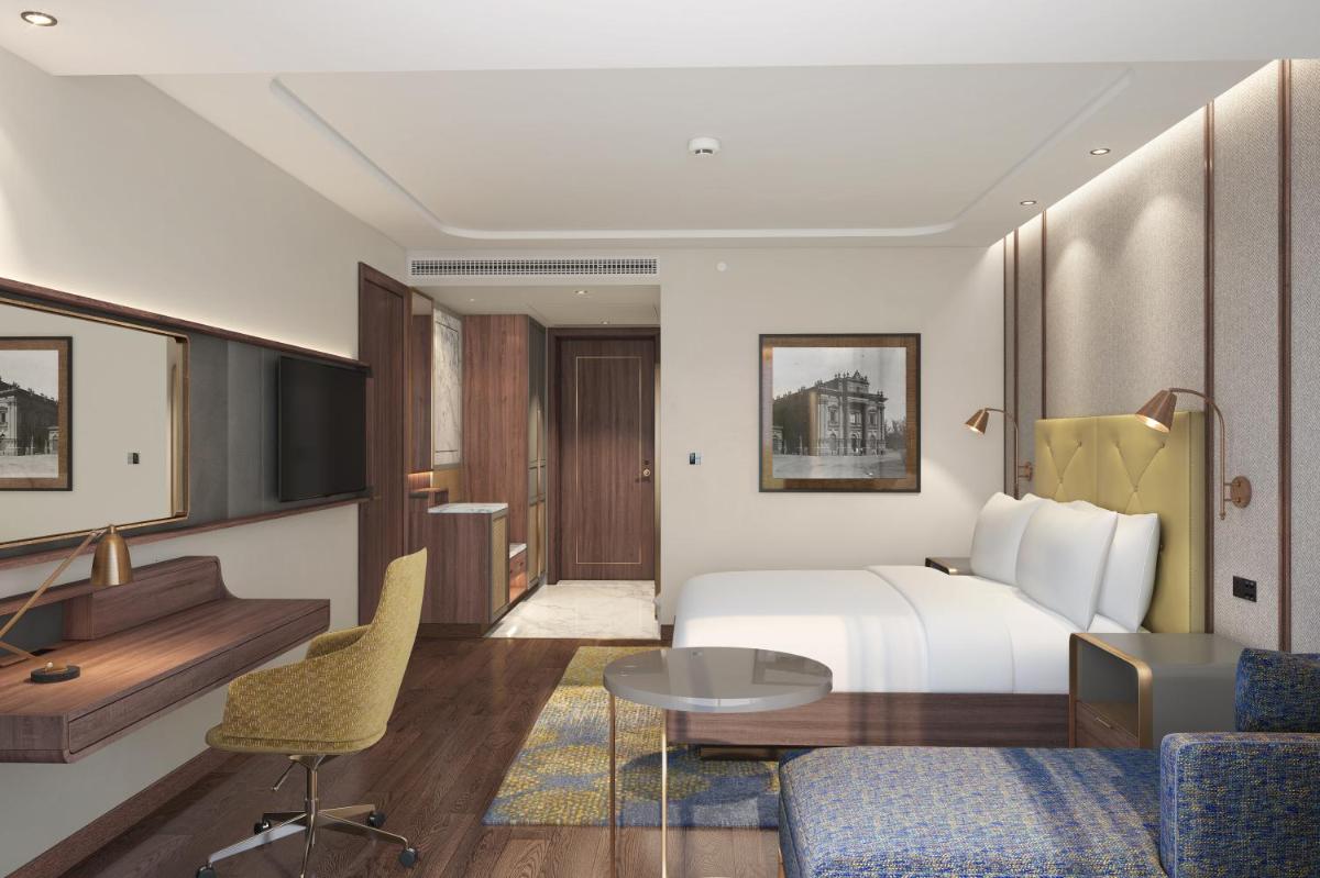 a hotel room with a bed and a table and chairs at Doubletree By Hilton Bengaluru Whitefield in Bengaluru