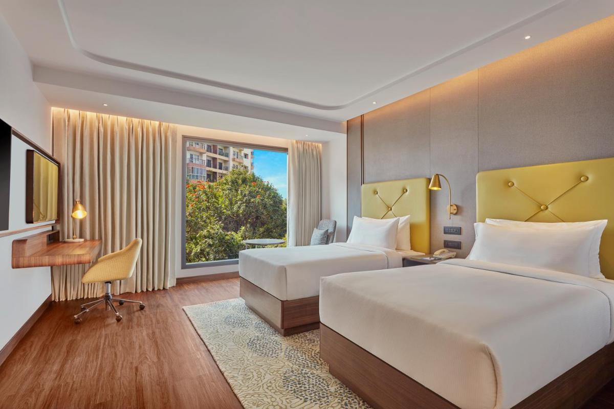a hotel room with two beds and a window at Doubletree By Hilton Bengaluru Whitefield in Bengaluru a hotel room with two beds and a window at Doubletree By Hilton Bengaluru Whitefield in Bengaluru