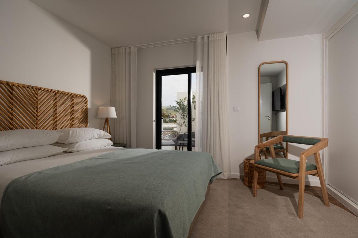 um quarto com uma cama, uma cadeira e um espelho em Alto do Forte em Ponta Delgada mais 288 fotografias