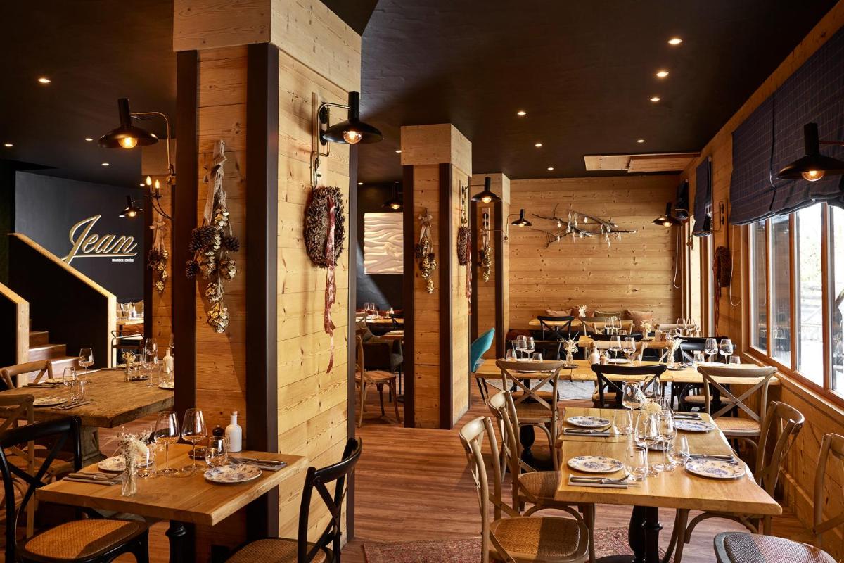 un restaurant avec des tables et des chaises en bois dans une salle dans l'établissement Hôtel L'Arboisie, à Megève