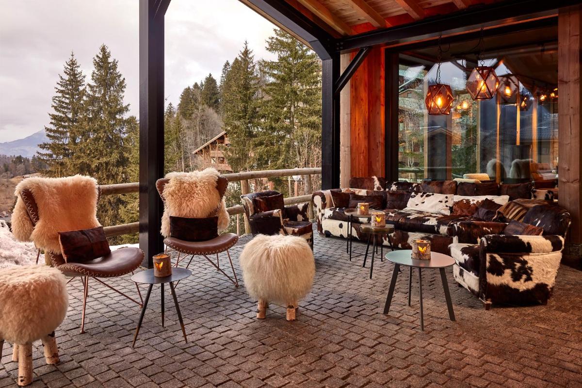 une pièce avec des peluches assises sur des chaises devant un bâtiment dans l'établissement Hôtel L'Arboisie, à Megève