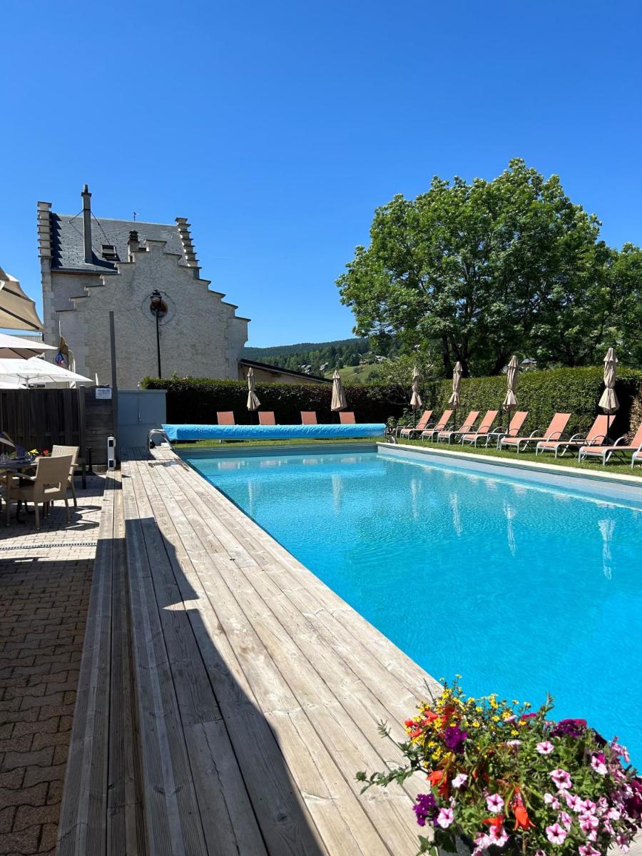 - une piscine avec une terrasse en bois et des chaises dans l'établissement Hôtel et Spa les Clarines, à Corrençon-en-Vercors