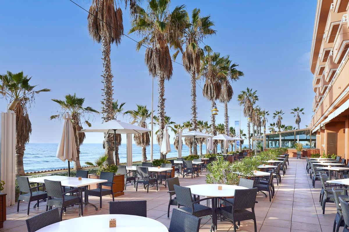 Un patio al aire libre con mesas y sillas y el océano. en Sunway Playa Golf & Spa Sitges, en Sitges 84 fotos más