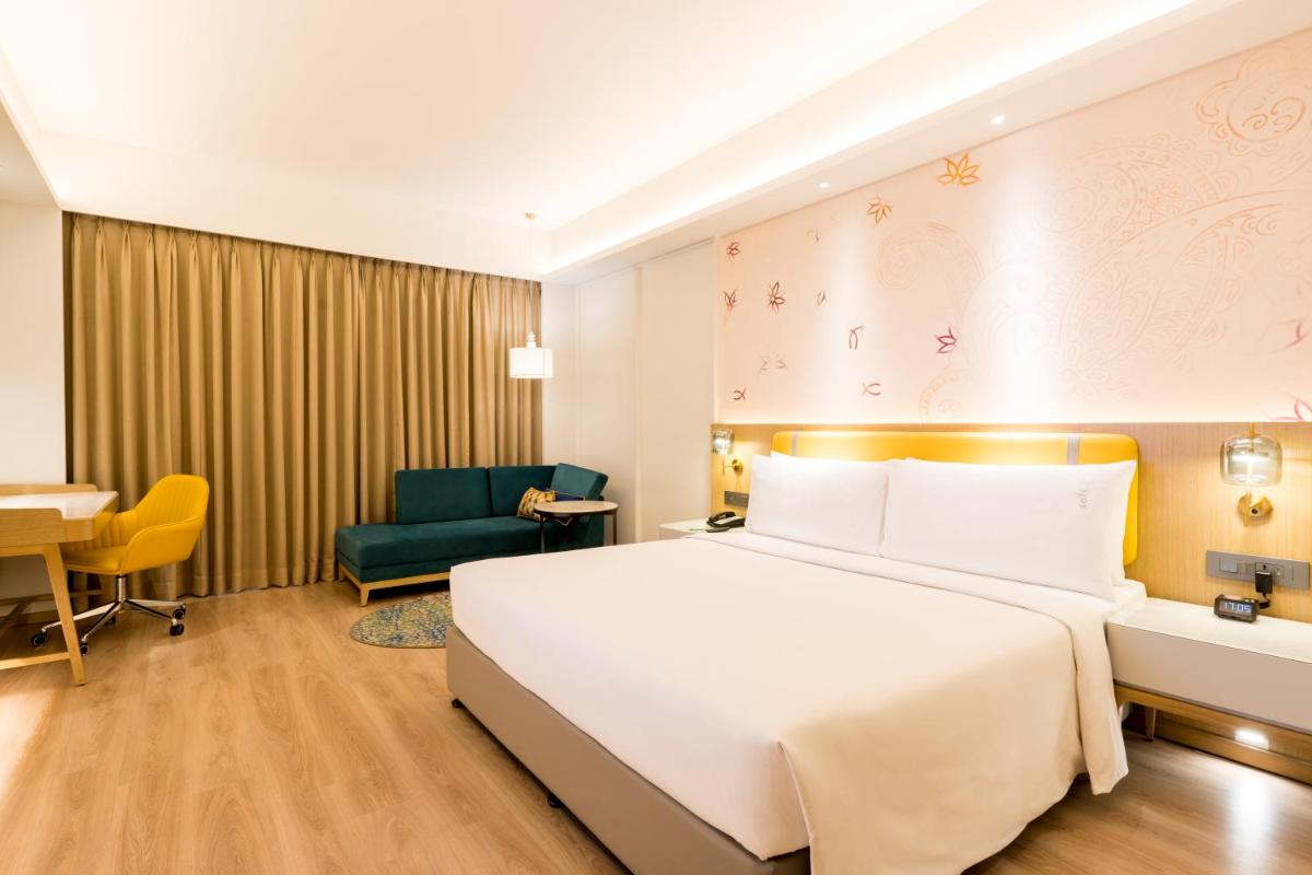 a bedroom with a large white bed and a desk at Holiday Inn Lucknow Airport by IHG in Lucknow