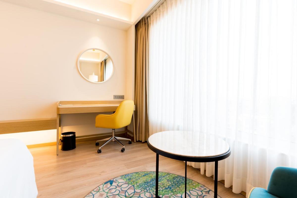 a room with a desk and a table and a yellow chair at Holiday Inn Lucknow Airport by IHG in Lucknow